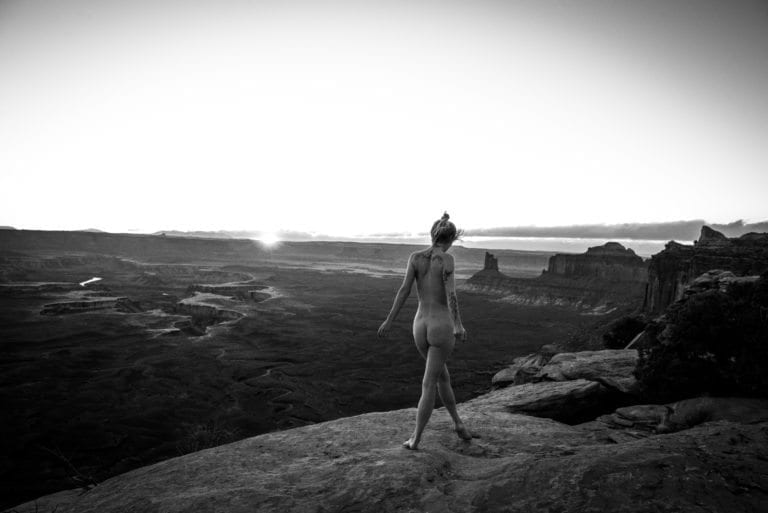 A nude woman walks along a cliff edge in Canyonlands National Park