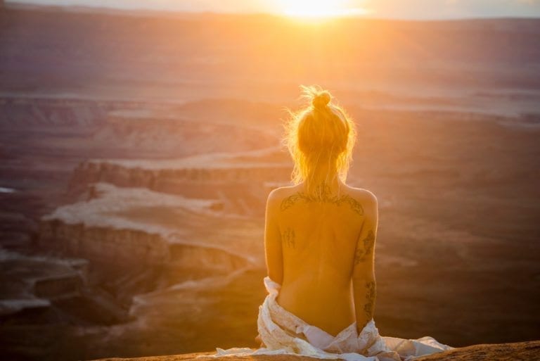 A topless woman looks into the setting sun in Canyonlands National Park