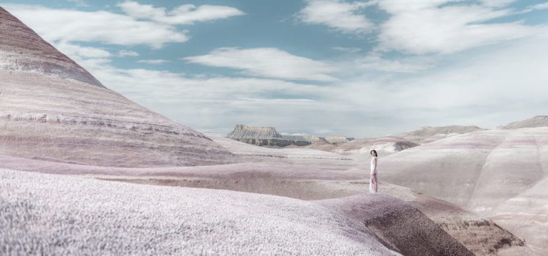 A woman in a white dress stands in a purple landscape