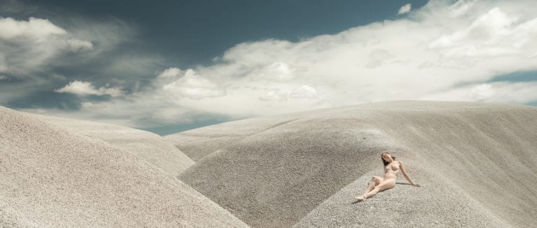 A woman lays nude on white sand dunes