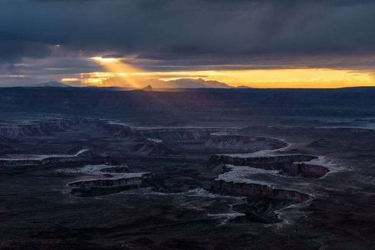Sun beam comes through clouds over the White Rim Trail in Canyonlands National Park, Utah