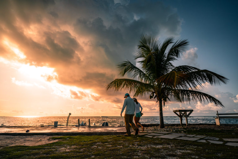 A man and woman walk to a boat in the Bahamas during sunset