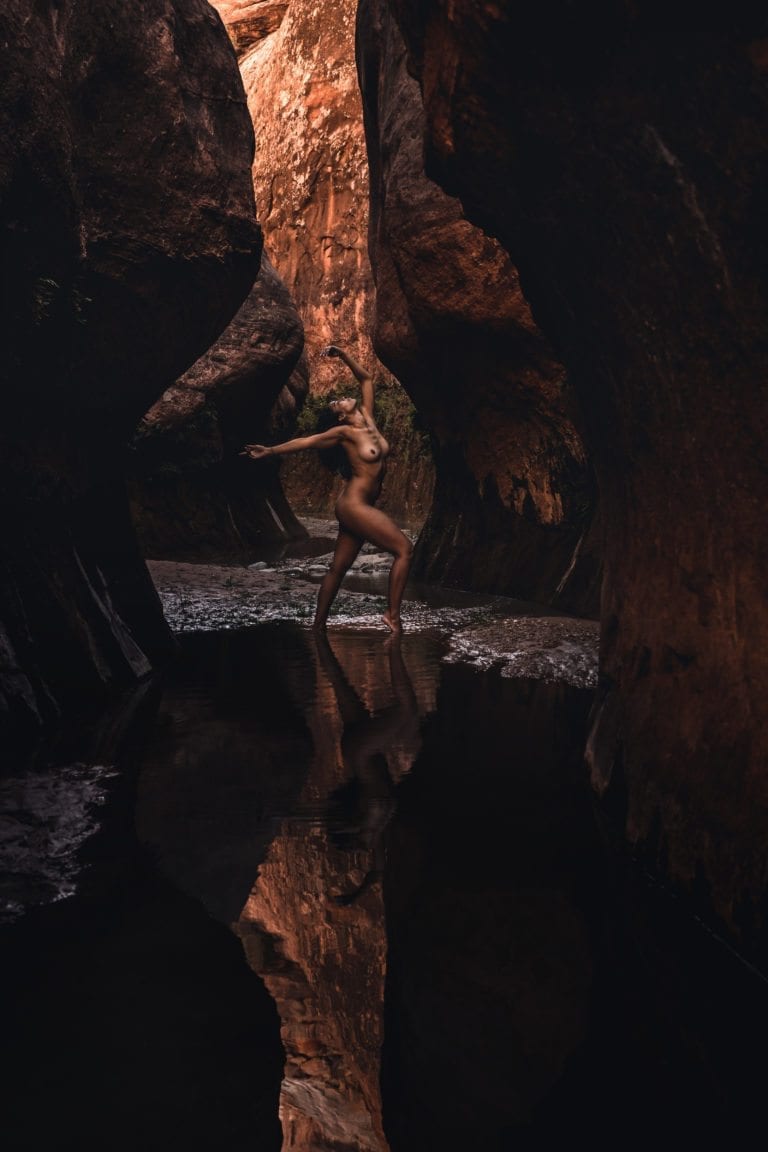 A black woman dances nude in the ambient light of a southern Utah slot canyon