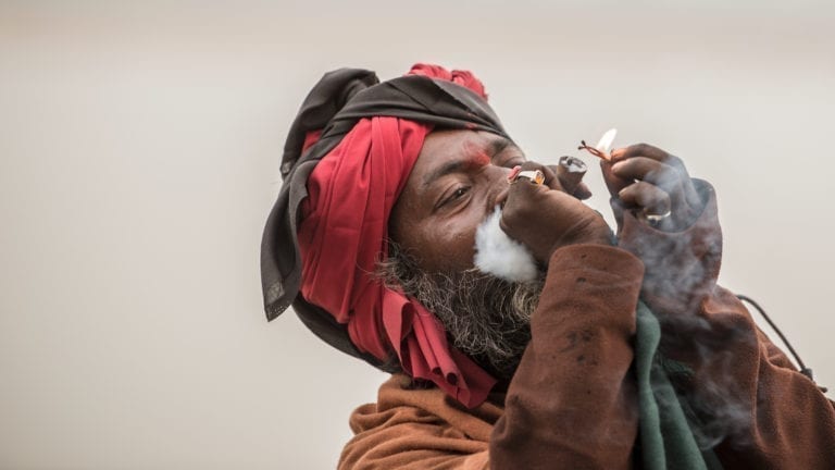 A man smokes a chillum on the banks of the Ganges River in Varanasi, India