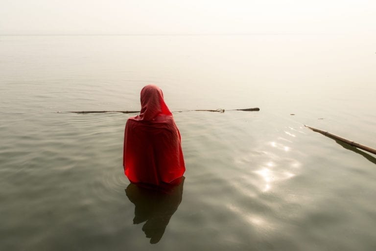 Woman praying in the Ganges River in Varanasi, India.