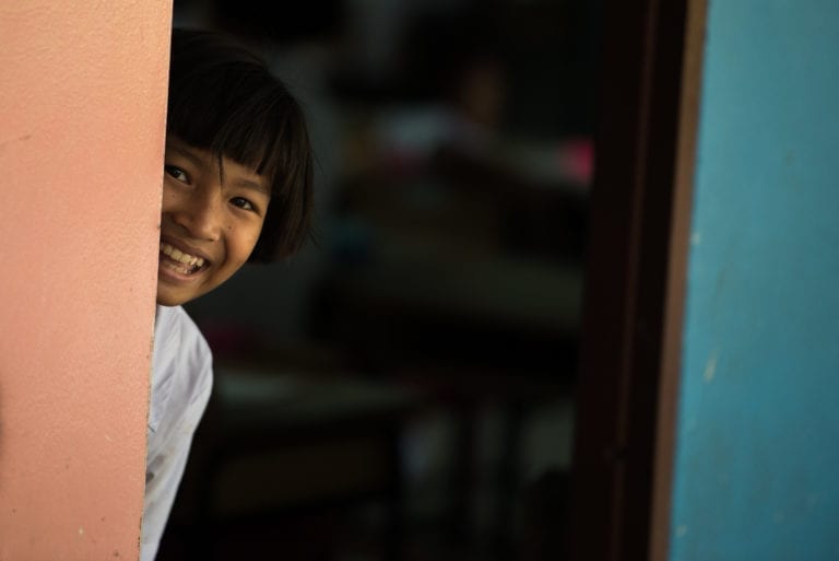 A young girl pokes her head out of a classroom in a Thai Orphanage