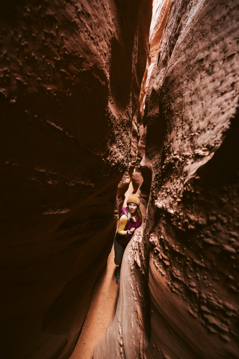 A woman squeezes through Spooky Canyon near Escalante, Utah