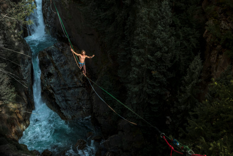 A man slacklines over a series of waterfalls.