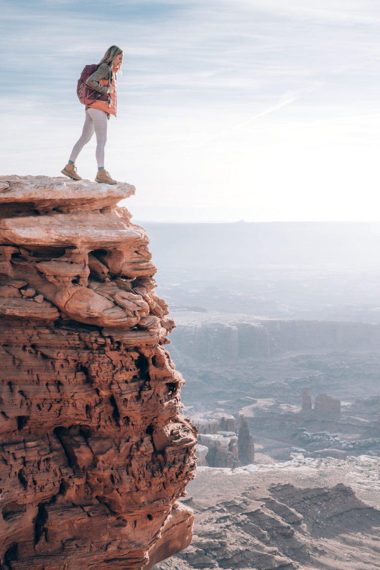A woman peers over the edge at Island in the Sky in Canyonlands National Park