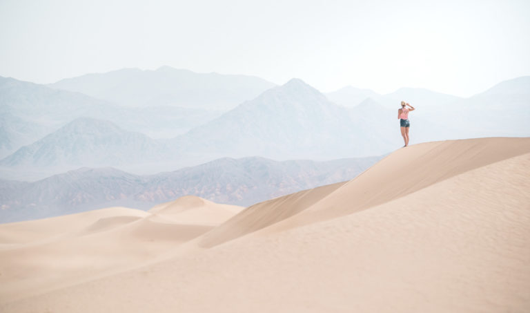 A woman stands on a sand dune in Death Valley National Park