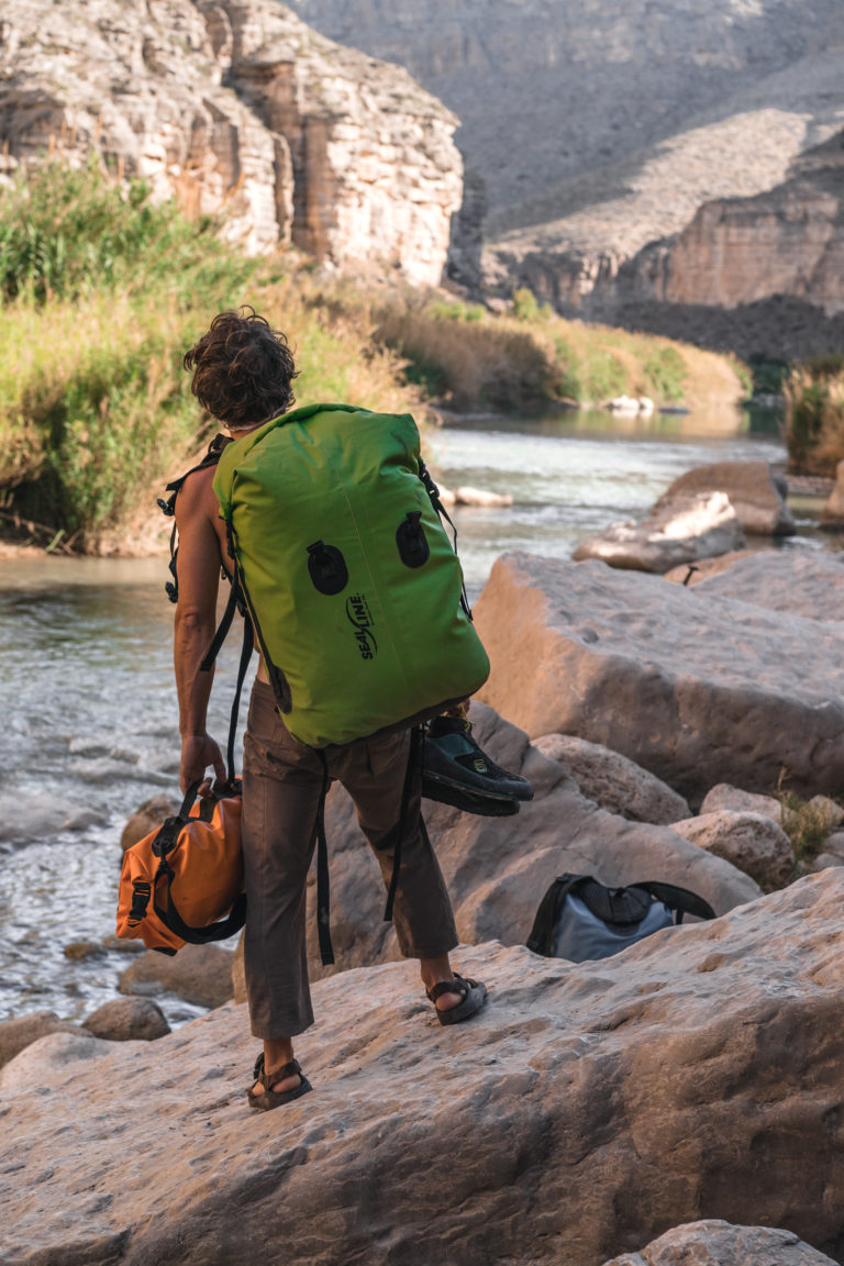 A man looks downstream with a SealLine dry bag backpack