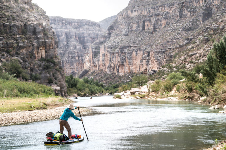 A standup paddleboarder paddles through the Lower Canyons of the Rio Grande River, Texas.