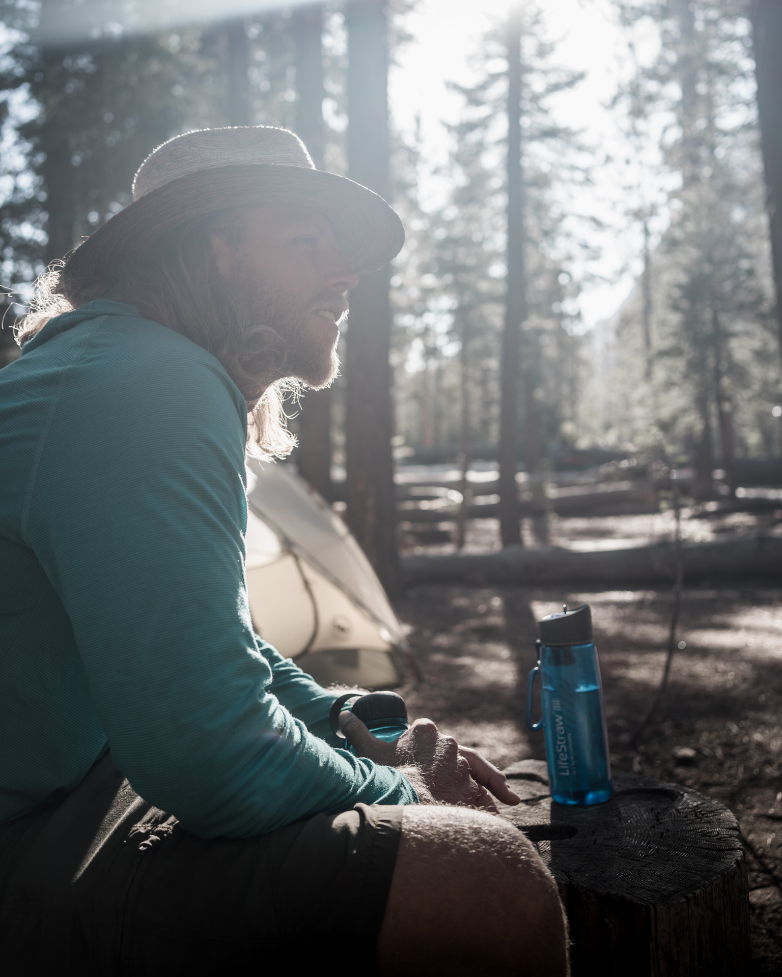 A man sits at camp with a Lifestraw Go waterbottle