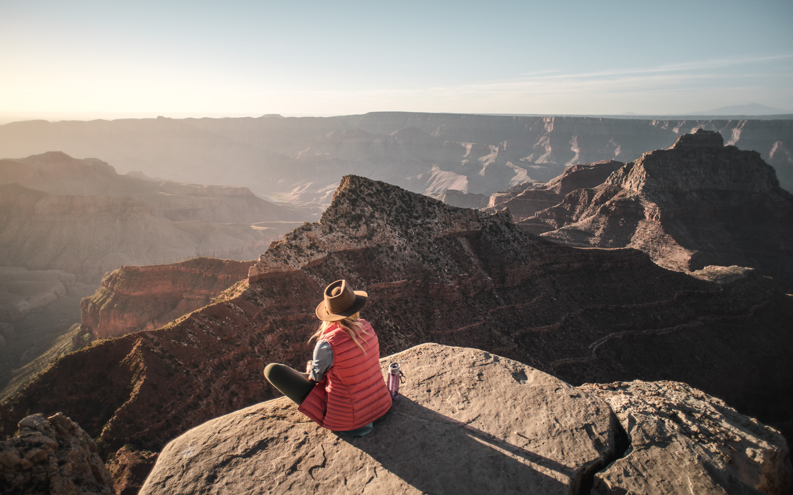 A woman sits on the edge of the Grand Canyon with a Lifestraw Go