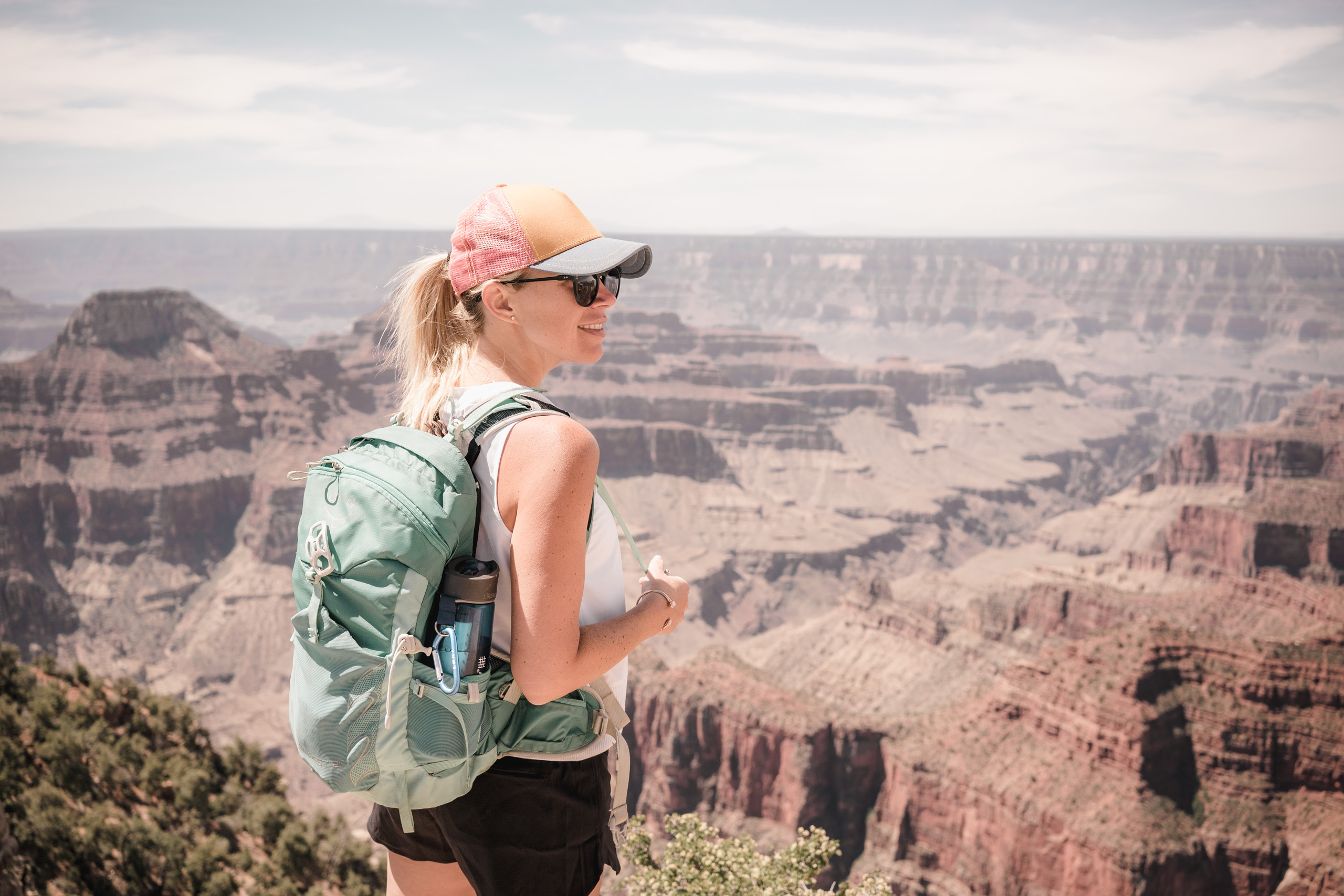 A woman looks out over the Grand Canyon with a Lifestraw Go in her pack.
