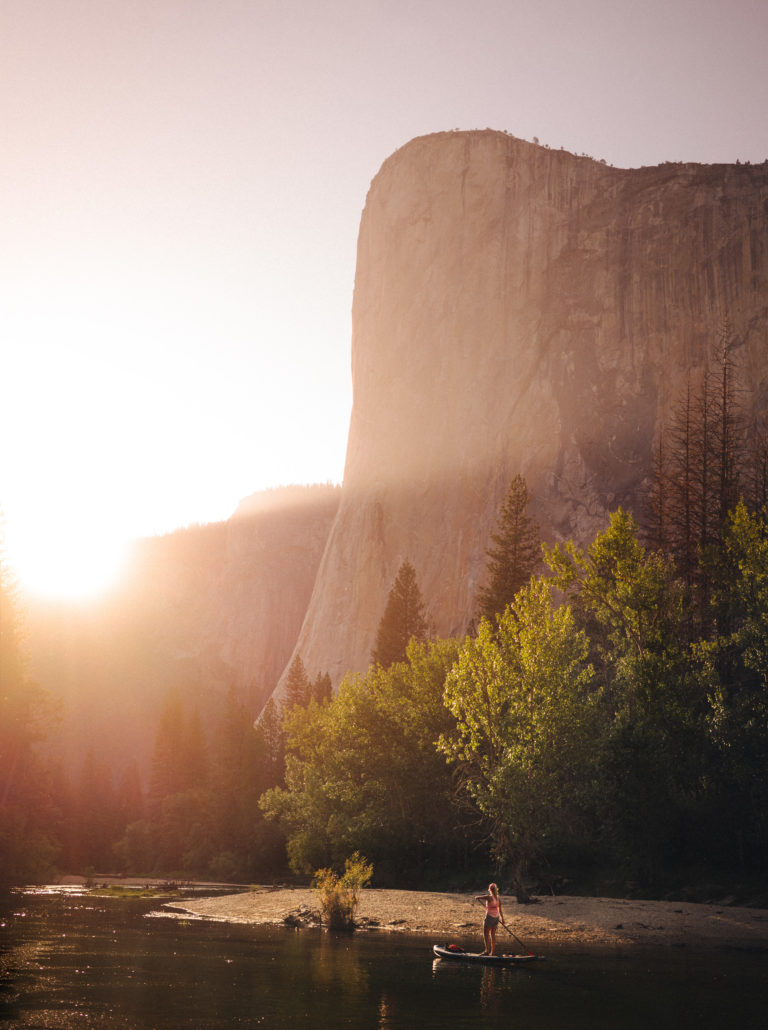 A woman standup paddles through Yosemite