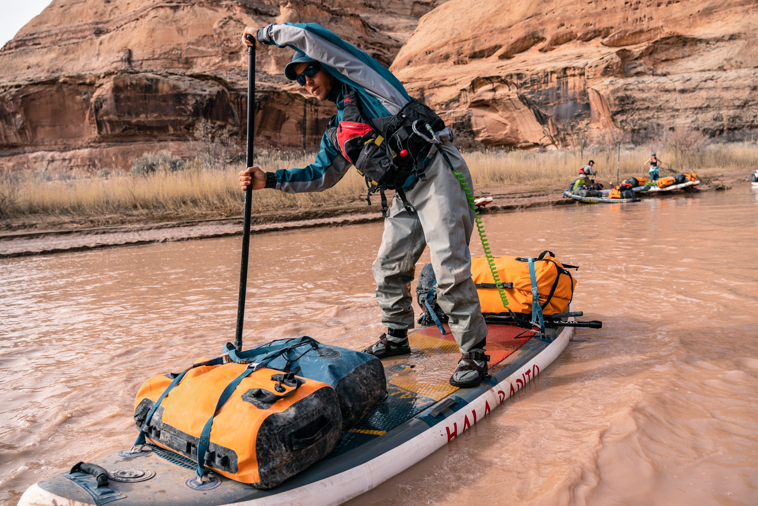 A man paddles a standup board loaded with SealLine bags