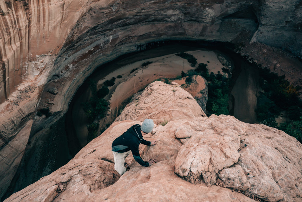 A man climbs down from Jacob Hamblin Arch