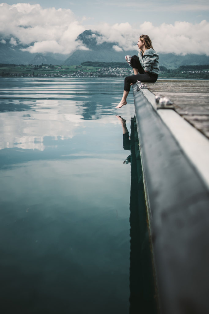 A woman sits on dock on Lake Brienz in Switzerland.