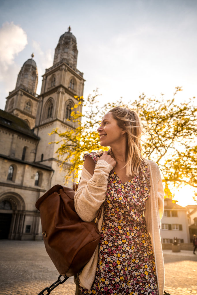A woman stands in front of Grossmunster, a cathedral in downtown Zurich.