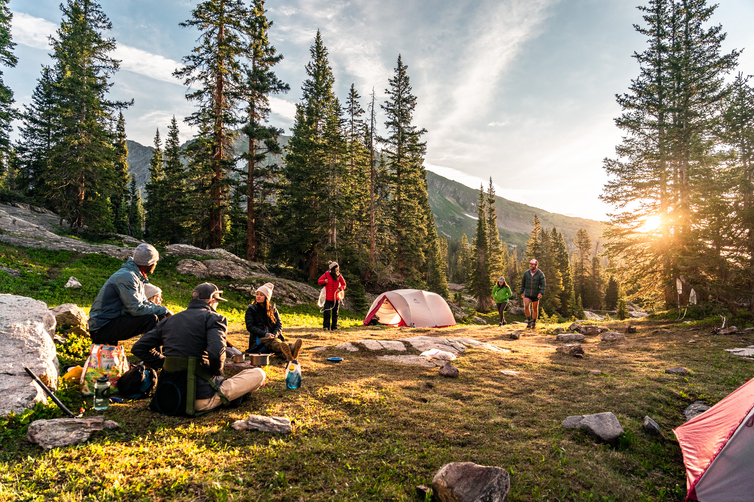 A group of people hang out early morning in the backcountry camp in the Colorado Rockies.