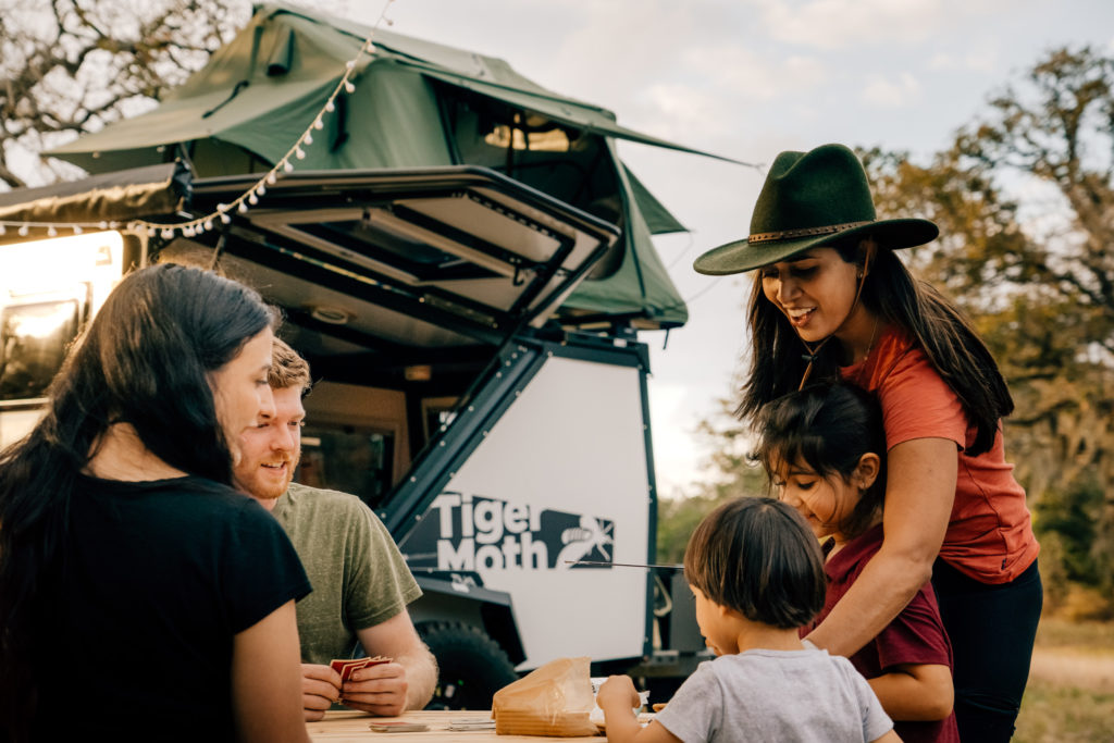 A family enjoys smors while camping with a Taxa Tiger Moth trailer.
